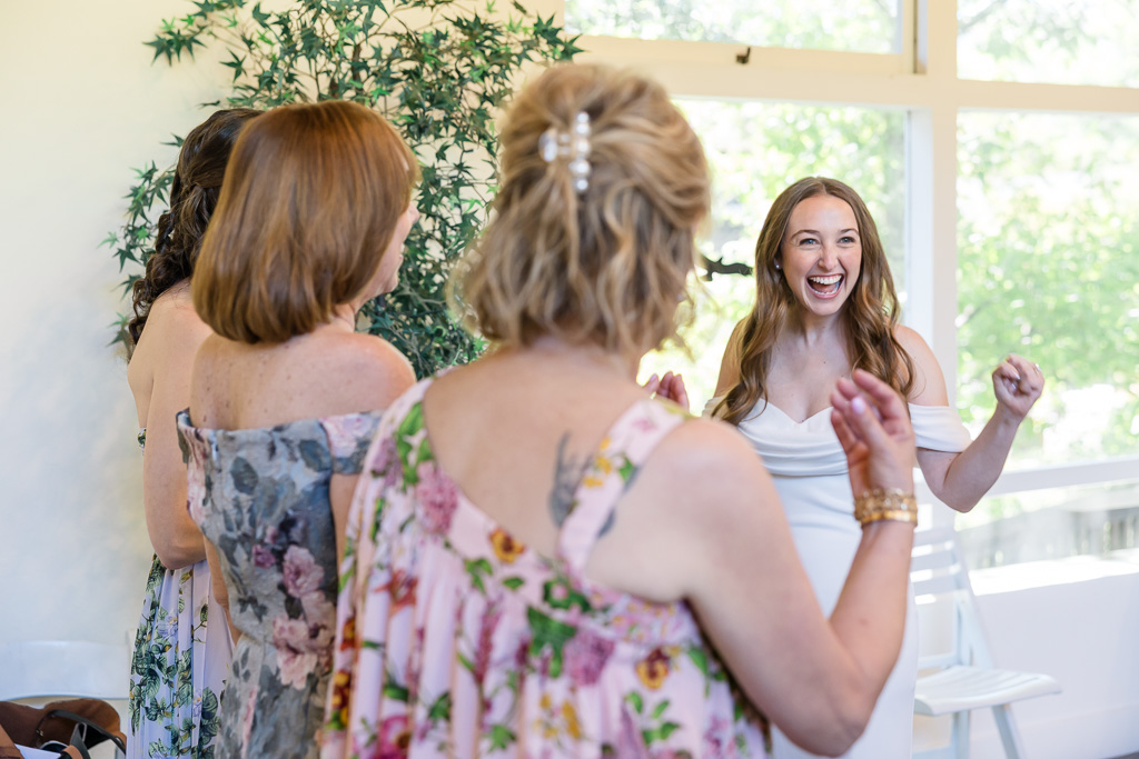 candid moment of bride laughing next to both moms
