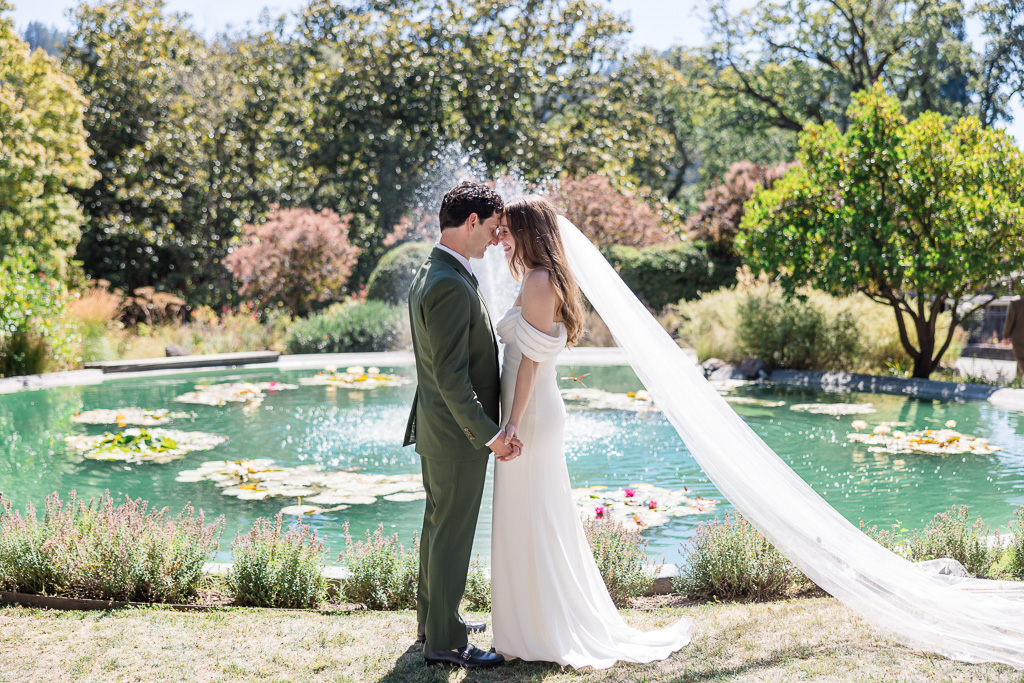 bride and groom in front of an outdoor fountain