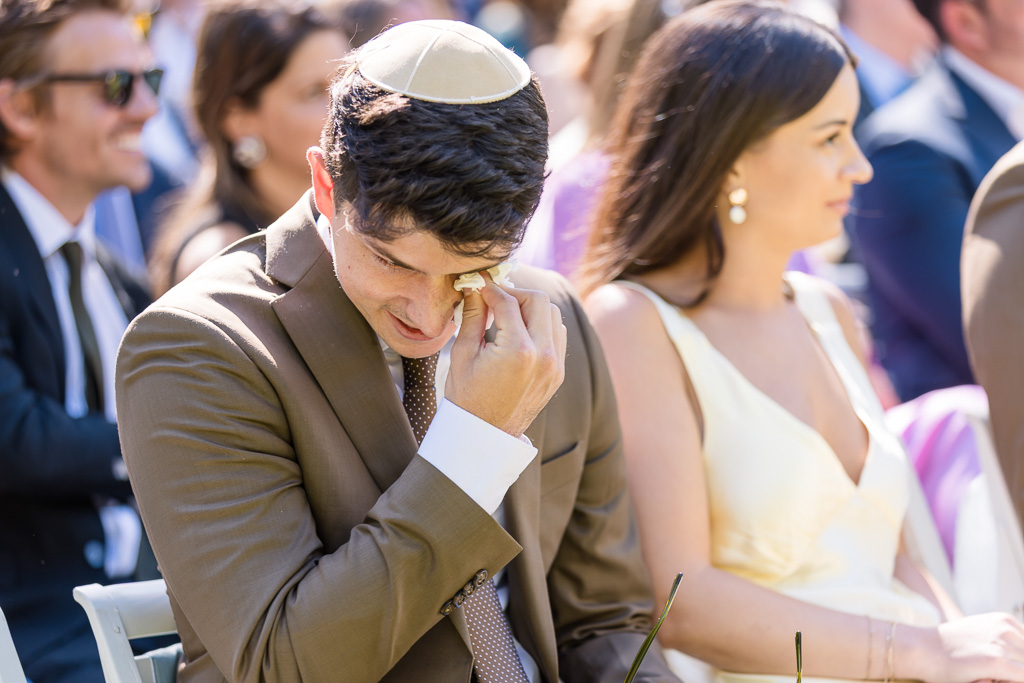 a wedding guest wiping away a tear during the ceremony