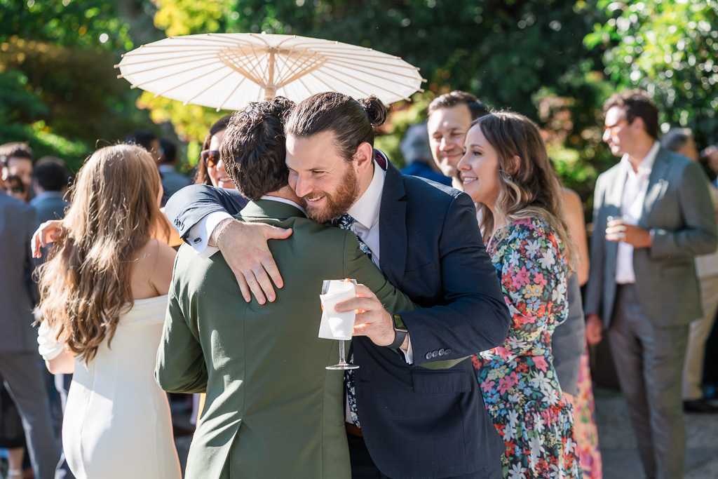groom greeting a friend at cocktail hour outside