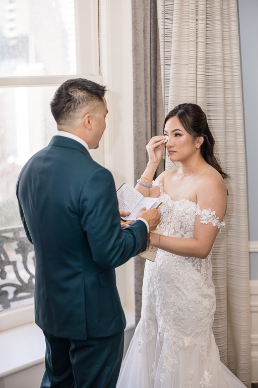 bride carefully wiping away a tear right after their first look