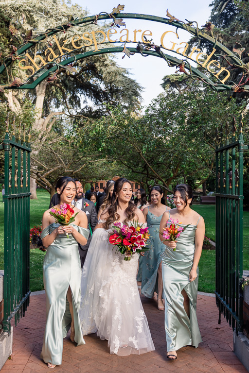 natural, organic photo of bride and bridesmaids walking under the Shakespeare Garden arch entranceway