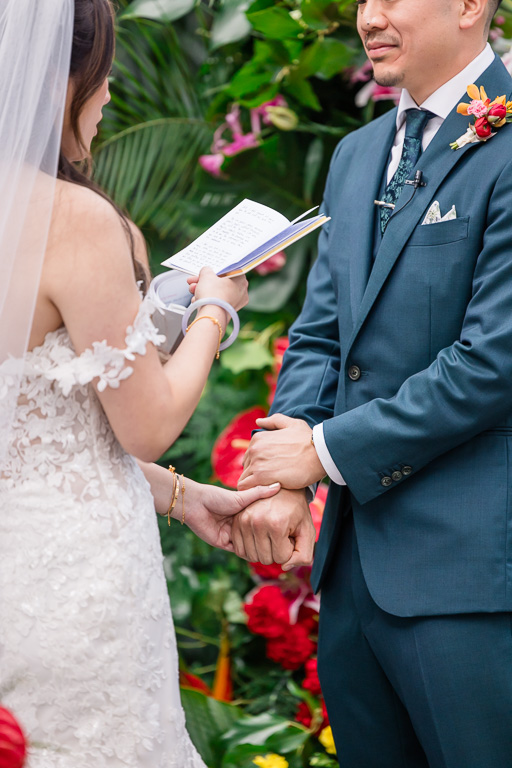 close-up of bride and groom holdig hands during vows exchange