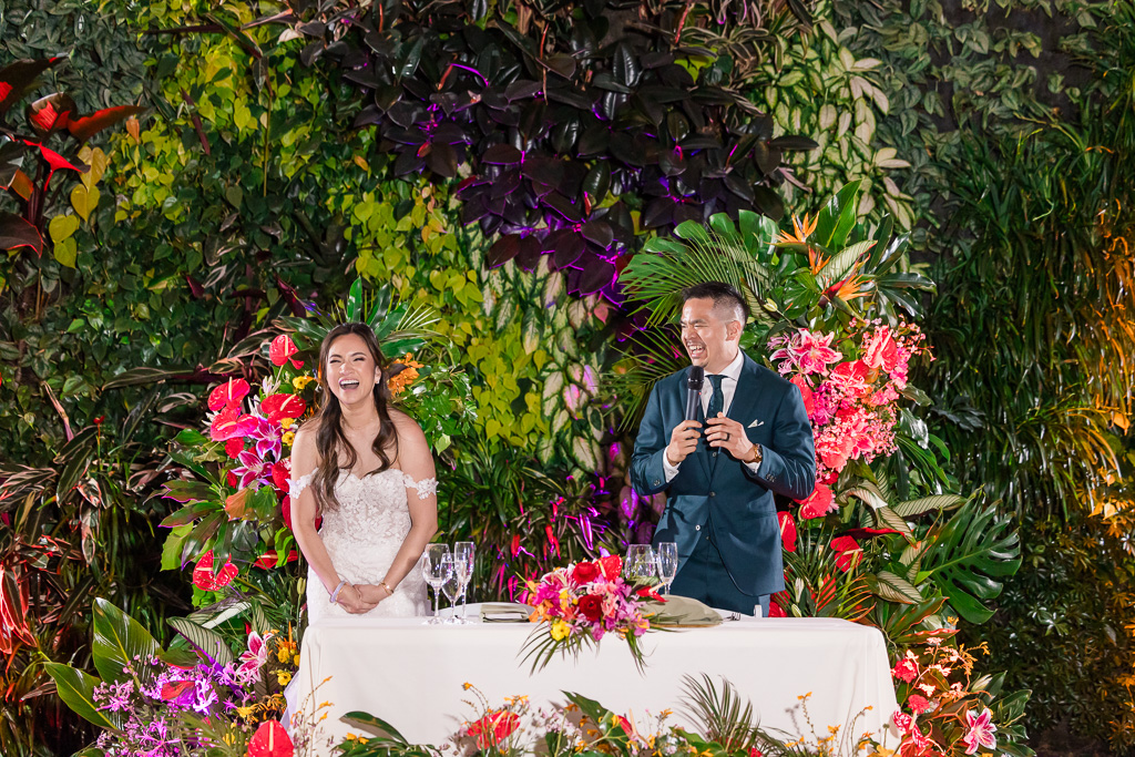 groom giving a welcome speech in front of the living wall