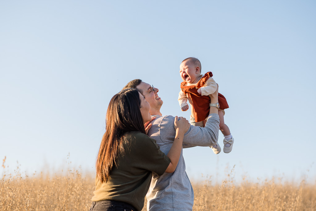 parents playfully tossing baby in the air