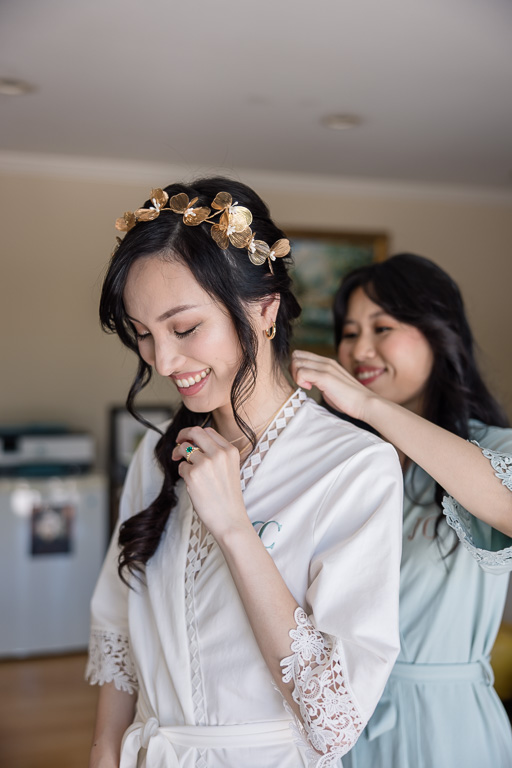 bridesmaid helping bride put on a necklace