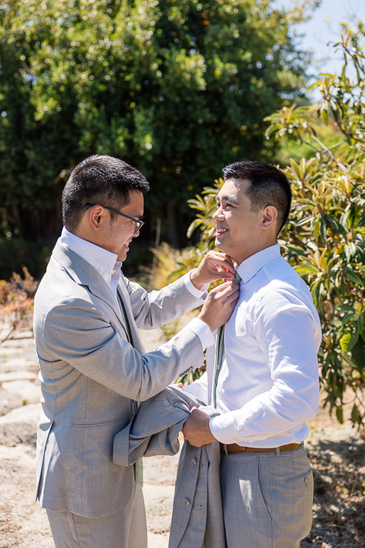 groomsman helping the groom tie his tie