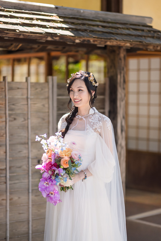 solo portrait of the bride holding her bouquet in front of a wooden Japanese style building
