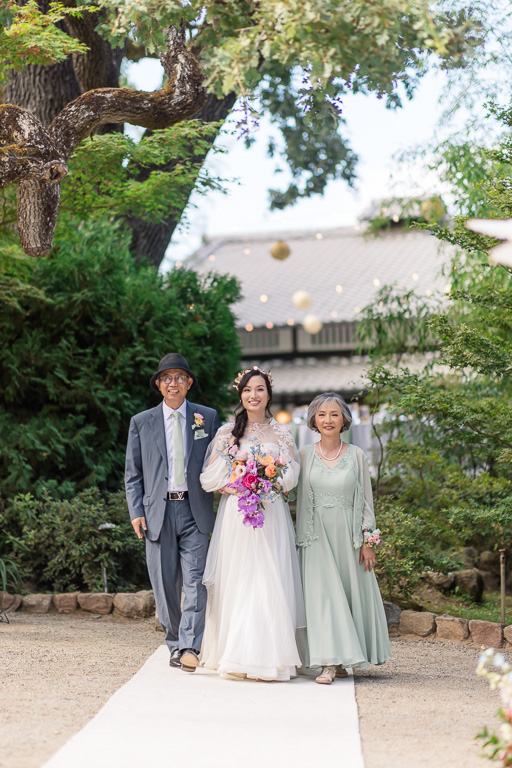 bride walking down the aisle with her mom and dad
