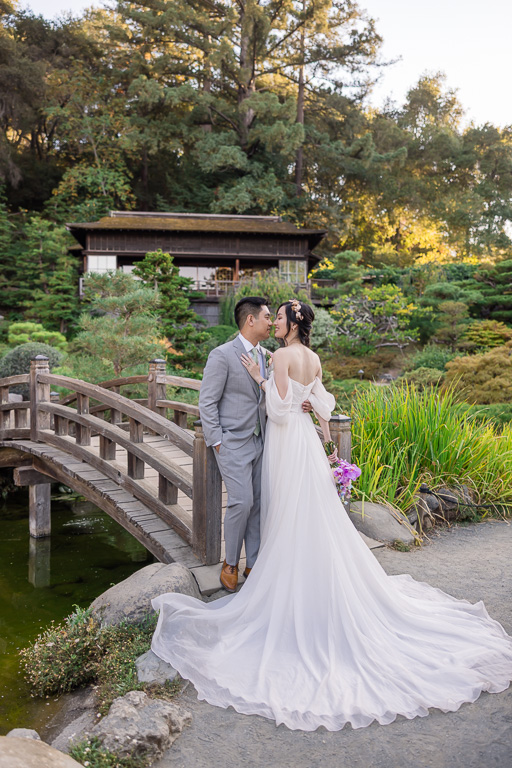 wedding portrait at wooden arch bridge over koi pond