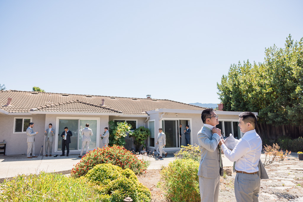 groom helping groomsmen with his tie