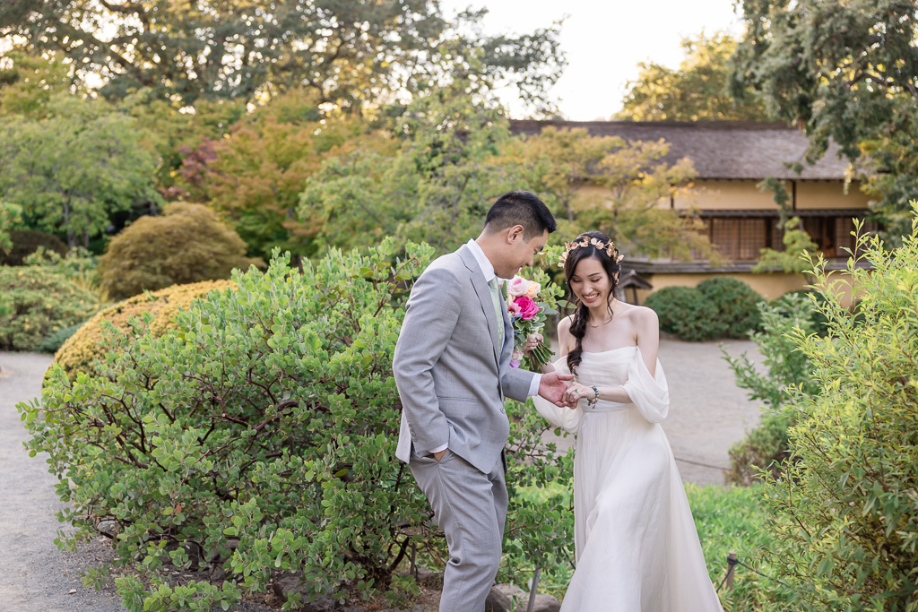 candid photo of the groom helping bride walk around gardens