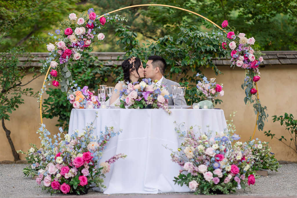 bride and groom sharing a kiss at their sweetheart table at Hakone Gardens