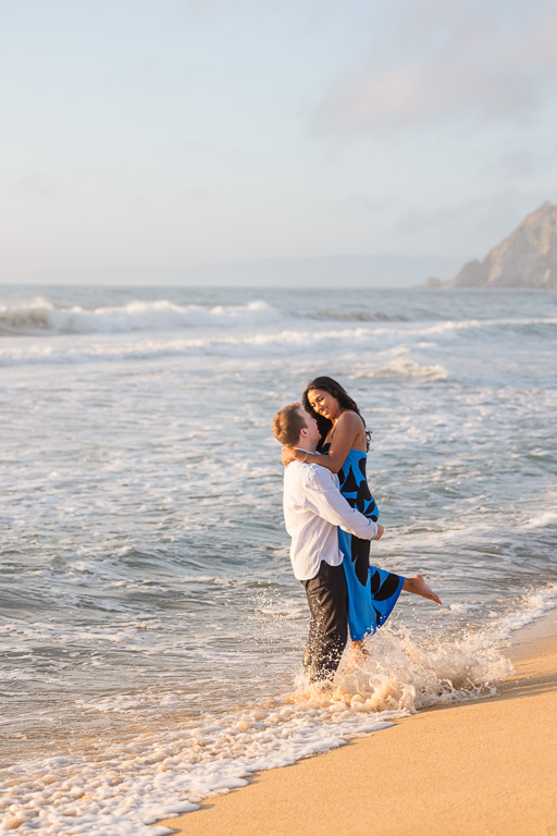 splashing in the beach water for engagement photos at golden hour