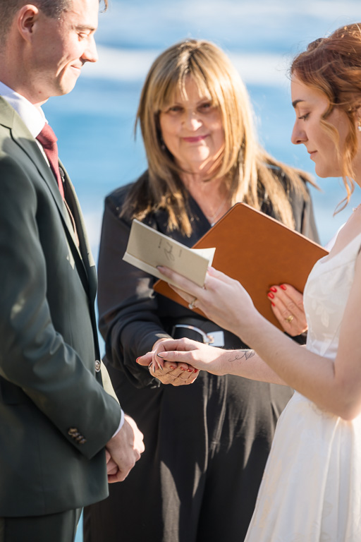 bride reading private vows from customized vow book by the ocean