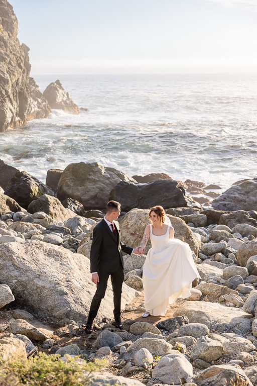couple walking along rugged oceanside rocks at Big Sur during golden hour
