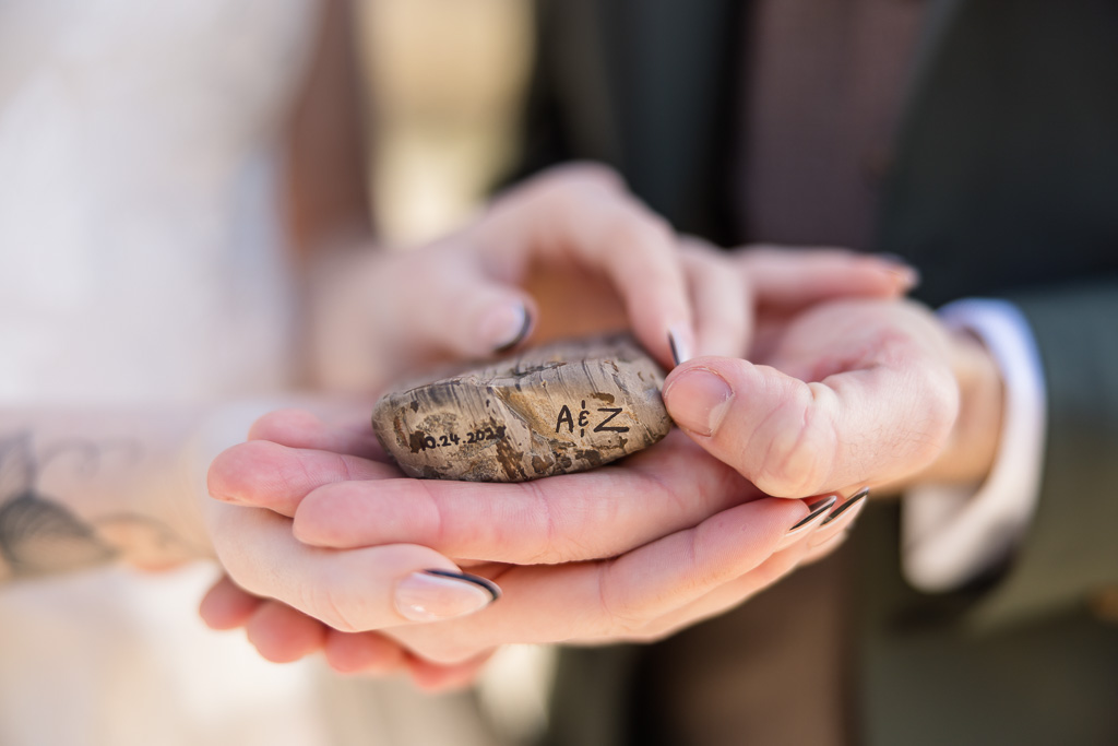 couple jointly holding a special rock with their initials and wedding date carved into it