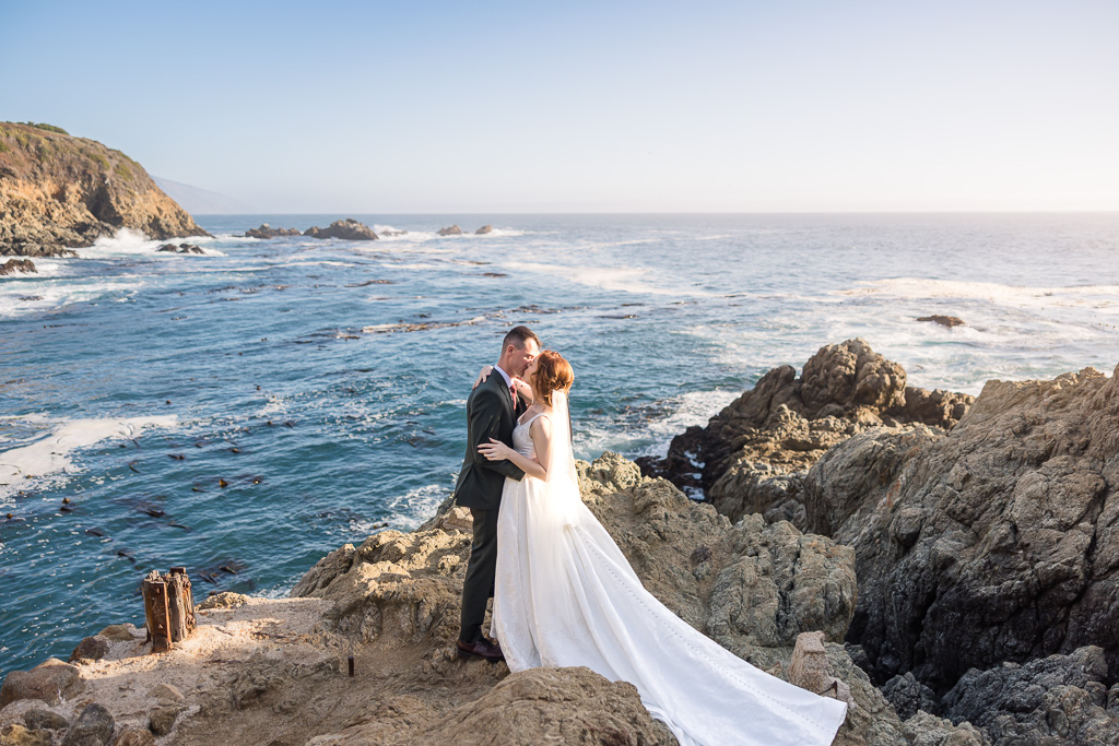 dramatic kissing photo of couple on the rocks above the ocean