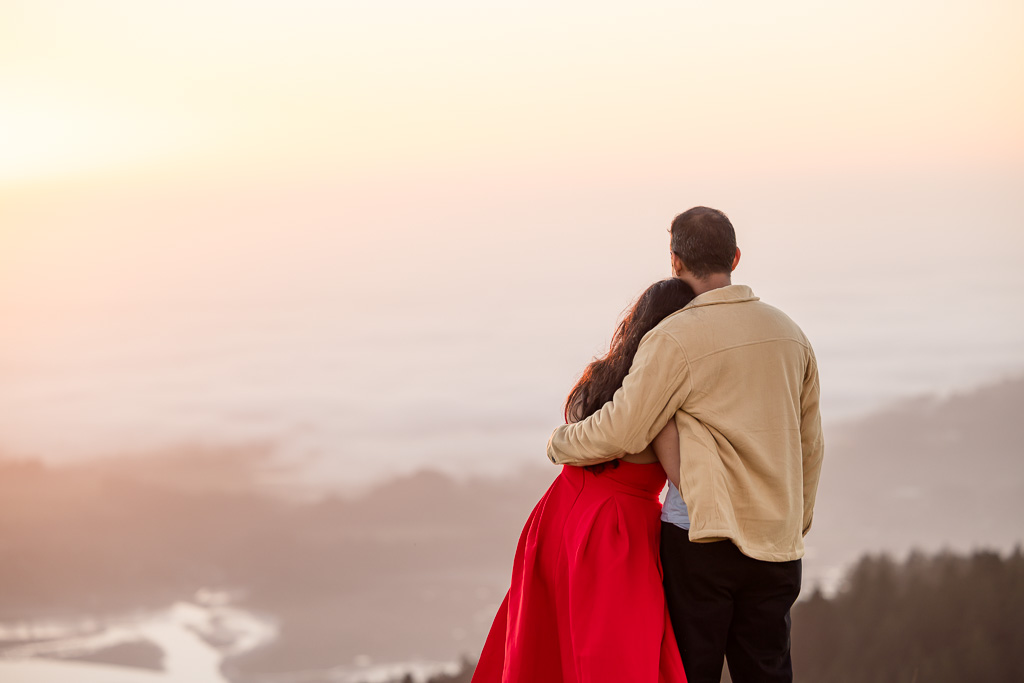 intimate photo of couple looking over a mountain towards the ocean sunset