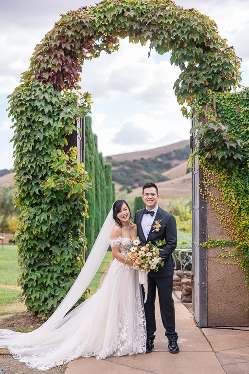 formal portrait of the couple looking at the camera under the arch at Viansa