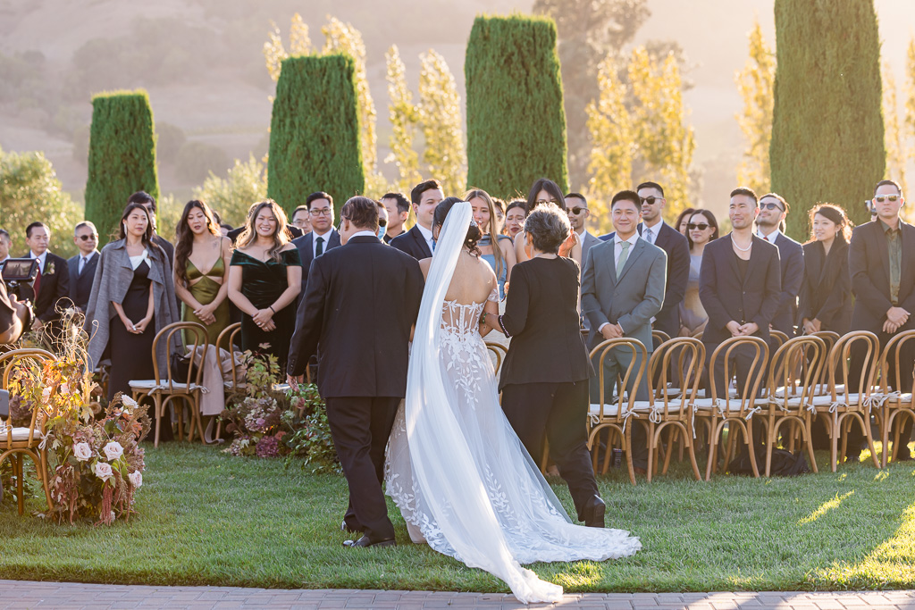 the bride walking down the aisle at Viansa with her parents while guests looking on