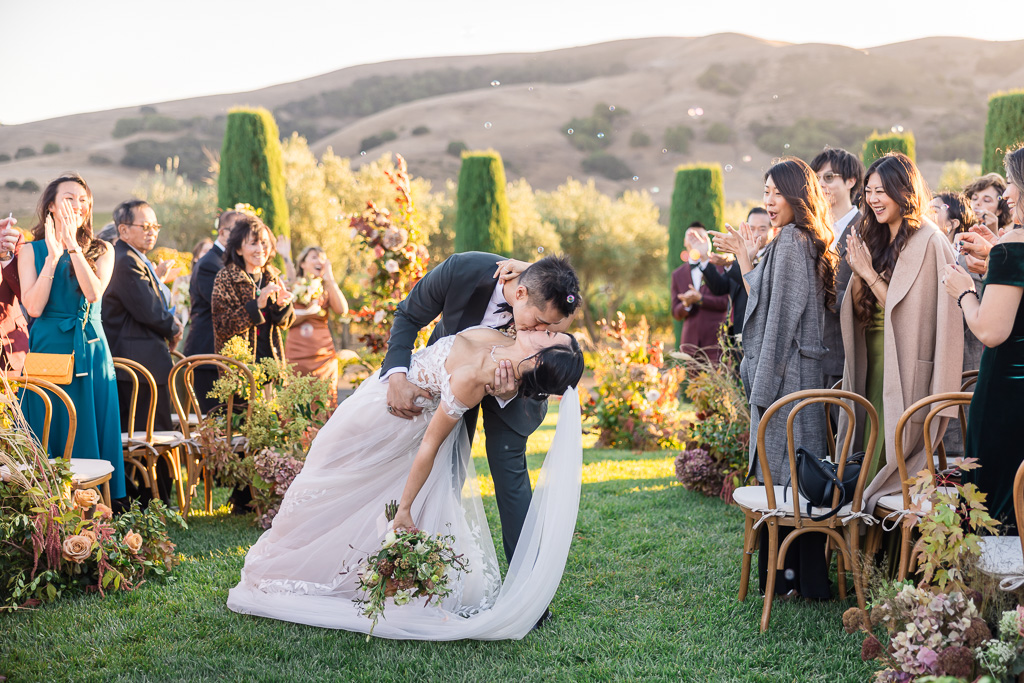 dip & kiss in the aisle with bubbles floating behind them