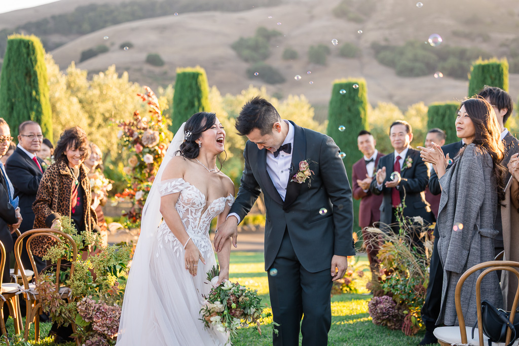 a joyous candid moment of the bride and groom while guests look on from behind