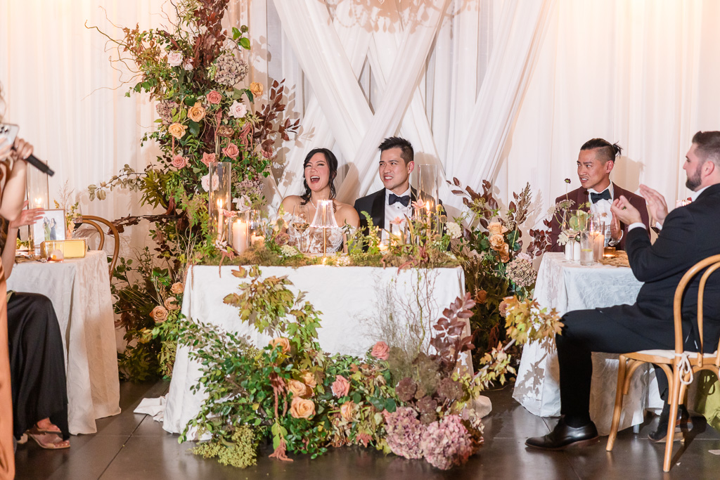 bride and groom laughing at a speech