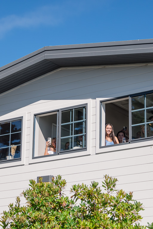 bridesmaids looking out the window while the bride and groom have their first look
