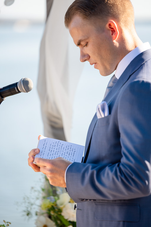 groom reading his handwritten wedding vows out of his vow book