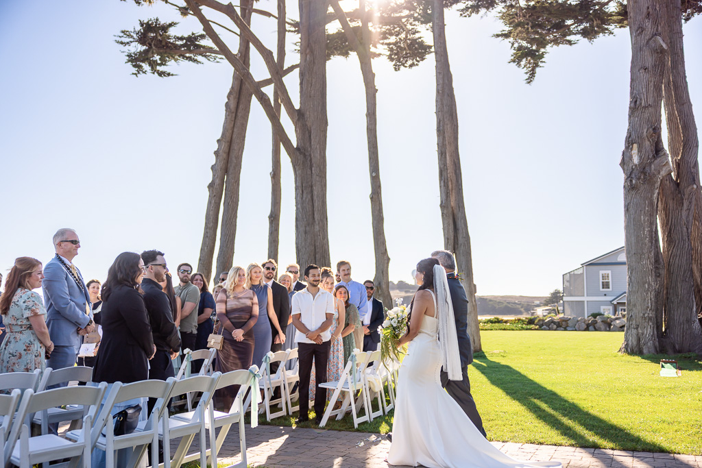 bride and dad walking up the aisle as guests stand and watch