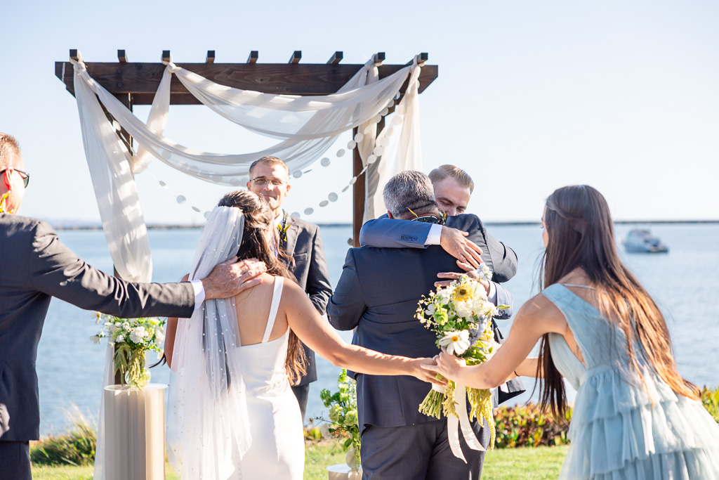 a hug between the groom and his father-in-law at the wedding ceremony