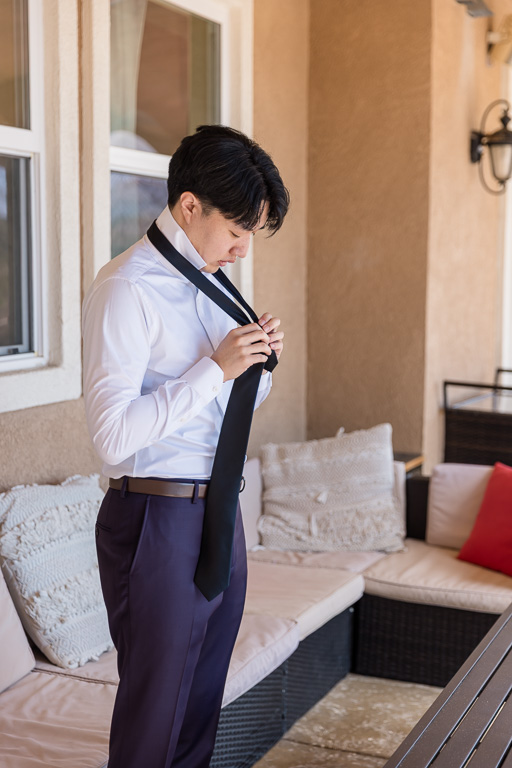 groom tying tie in the backyard