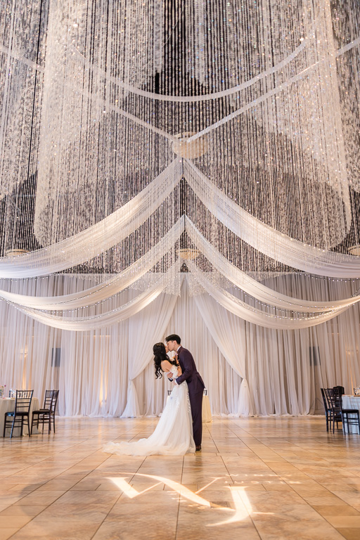 a dip and kiss under crystal chandelier in ballroom