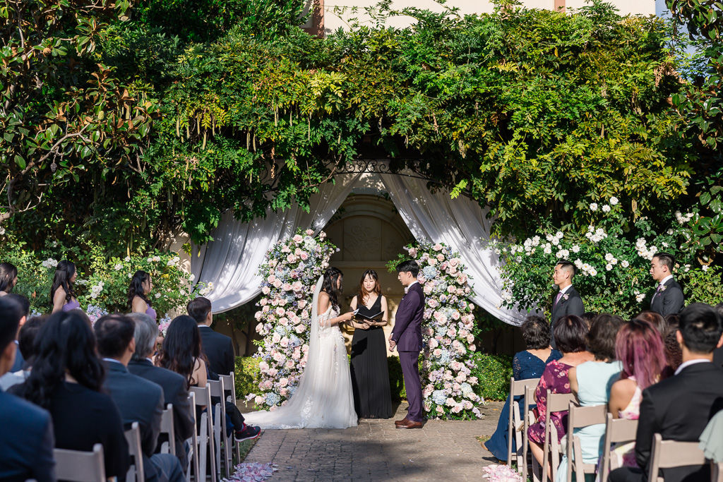 Outdoor wedding ceremony under floral arch