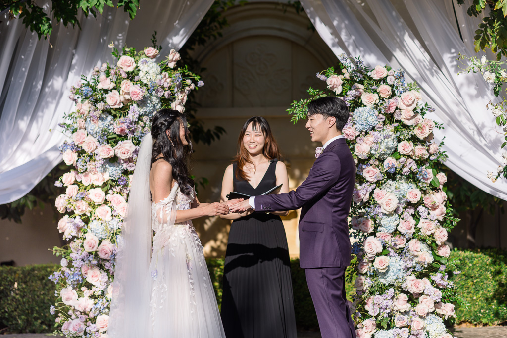 Bride and groom exchanging vows during outdoor ceremony with their friend as the officiant