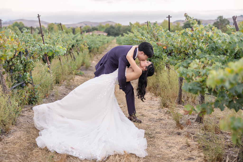 Groom dipping bride for kiss in Casa Real vineyard