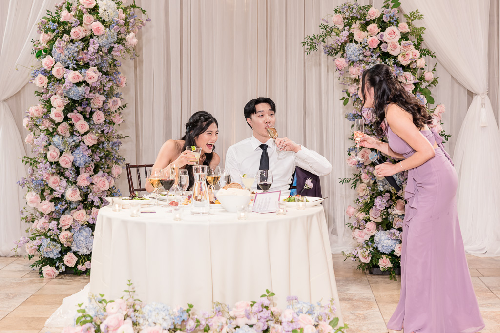 Bridesmaid toasting newlyweds at sweetheart table