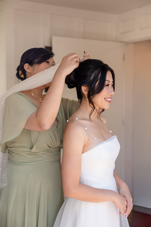 sister of the bride putting her veil in