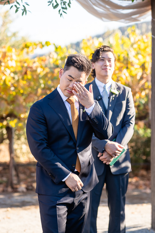 groom wiping away a tear as the bride walks down the aisle