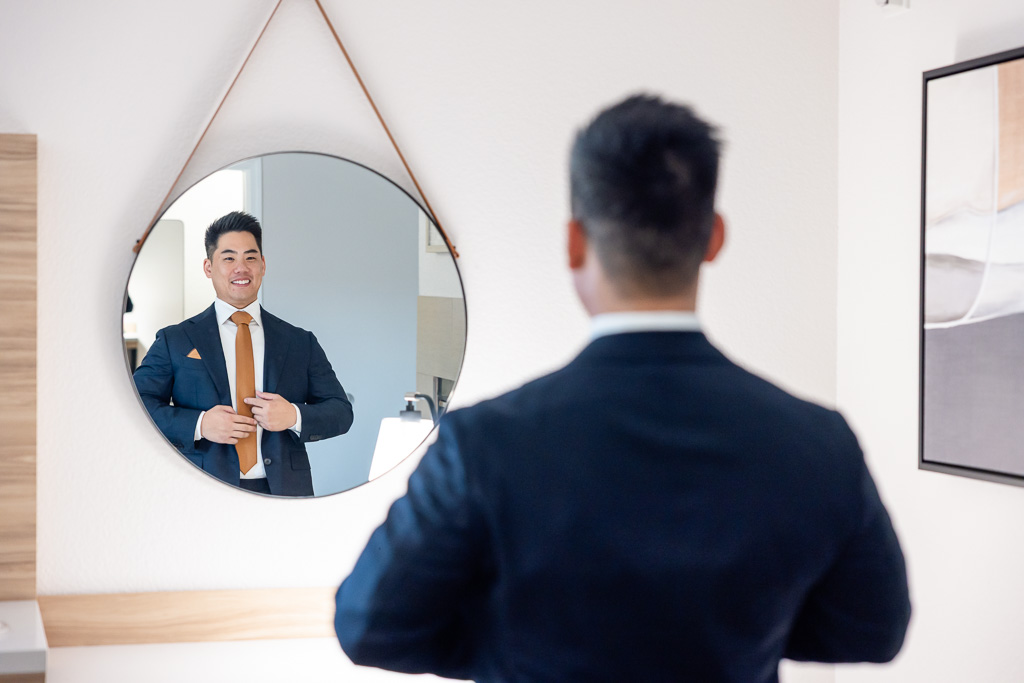 groom looking in the mirror straightening up his jacket