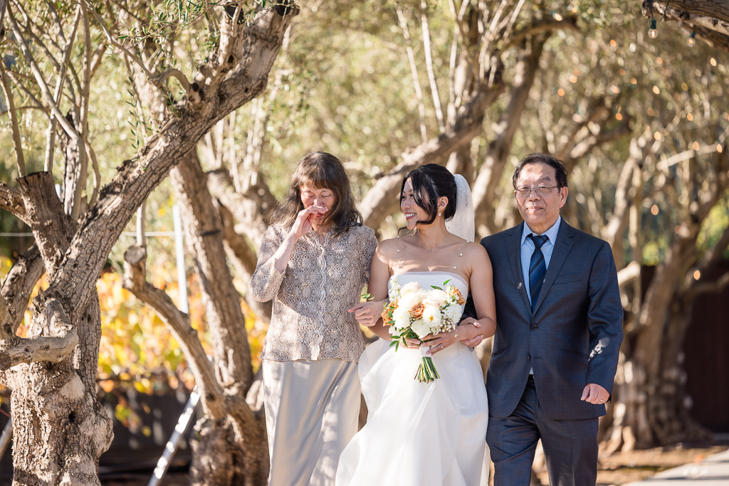 bride walking up the aisle with both of her parents