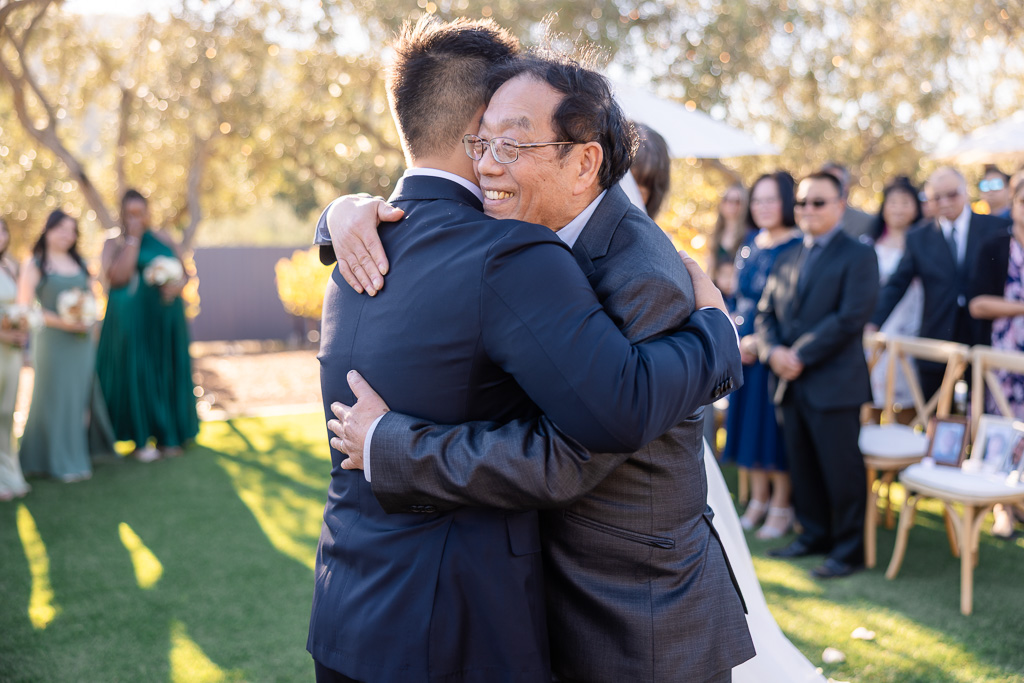 dad smiling as he hugs the groom in the bride exchange