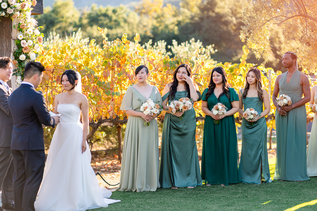 bridesmaid wiping away a tear as the groom says his vows