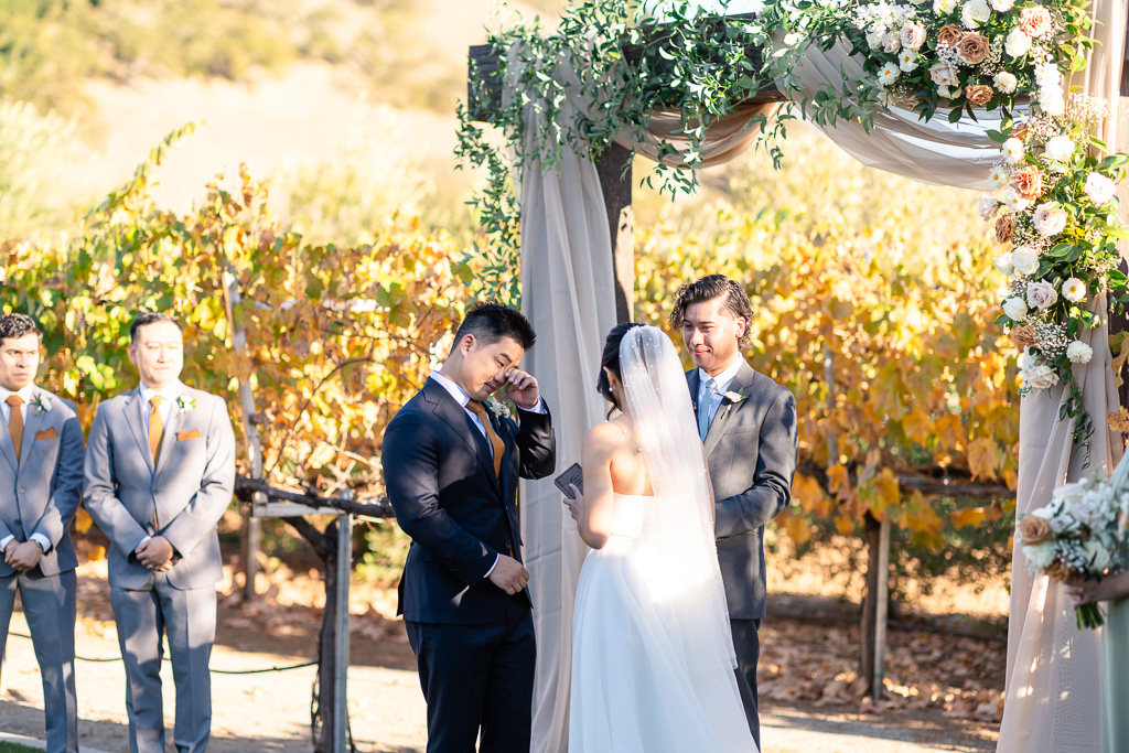 groom wiping away a tear as the bride says her beautiful vows
