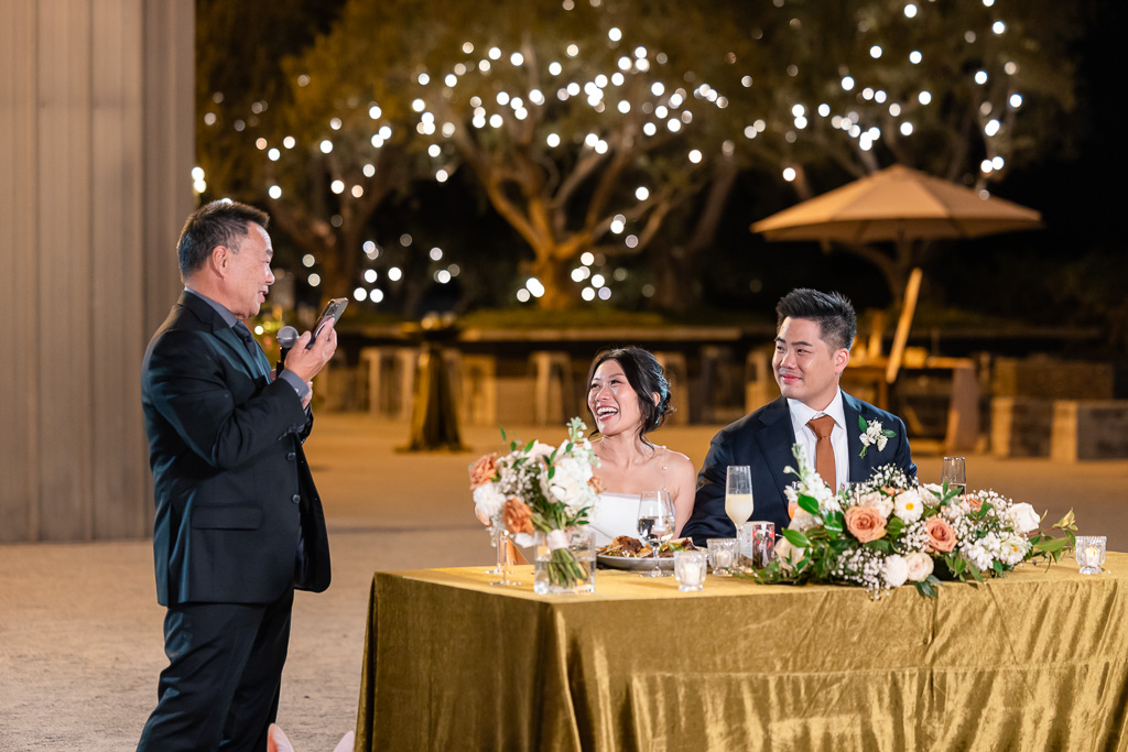 father of the groom giving a dinner toast outdoors at nighttime