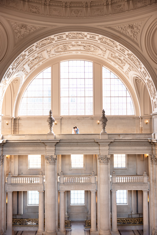 faraway shot showing the bride and groom and a beautiful, wide view of City Hall's large arch windows