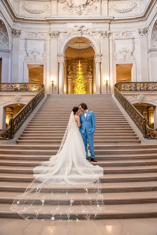 groom and bride with long, airy, thin gossamer veil on SF City Hall steps