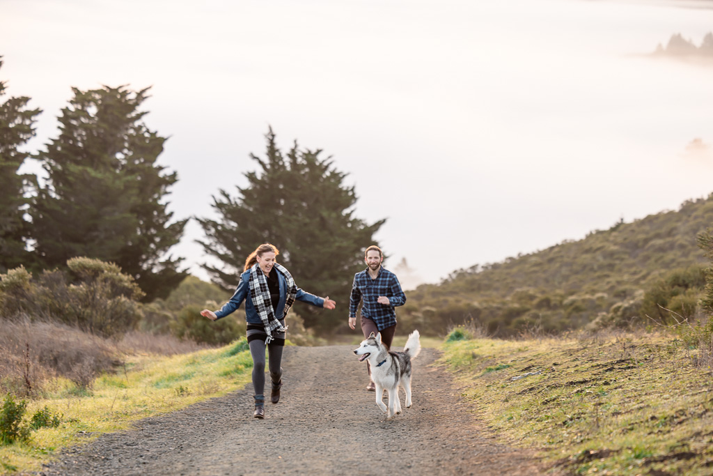 couple running along a trail with their dog