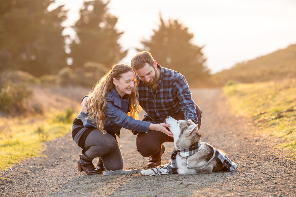 couple playing with their Husky dog in golden morning light
